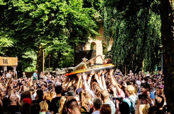 Man met saxofoon crowdsurfen
