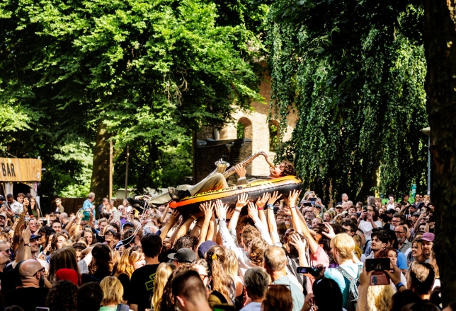 Man met saxofoon crowdsurfen